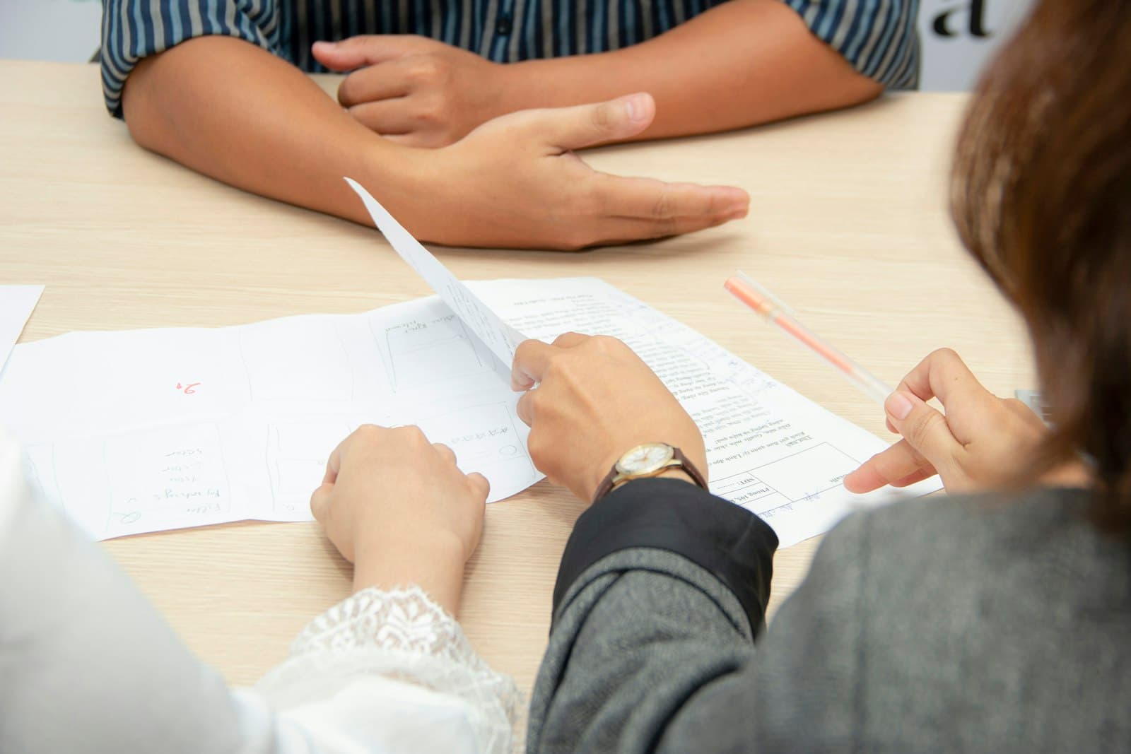Two people seated at a table reviewing and pointing at printed documents — executor selection consultation